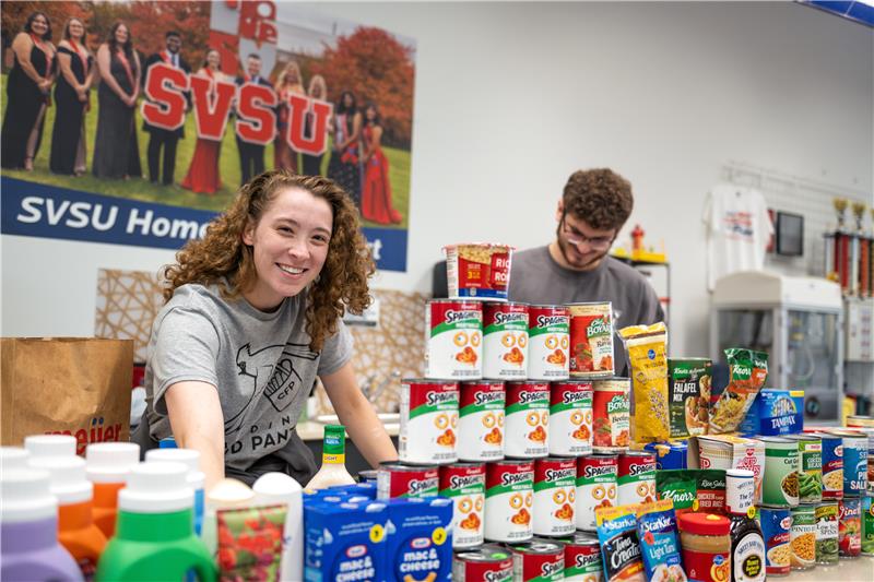 Two students organizing stacks of non-perishable food items after a Cardinal Food Pantry donation event.